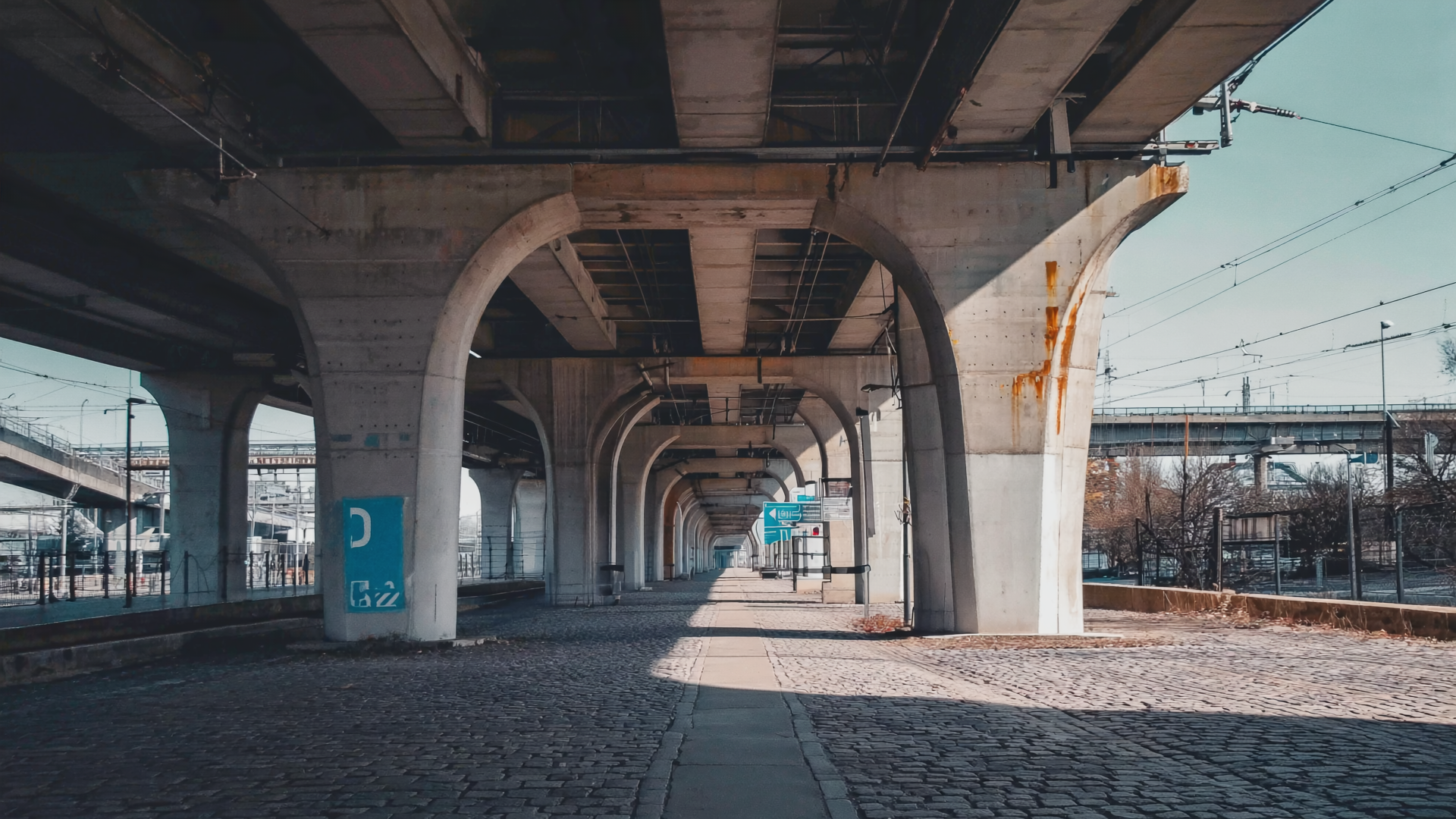 Konkreter Brückenpfeiler einer Berliner S-Bahn-Trasse im Schatten, mit einer kobaltblauen Markierung am Sockel.